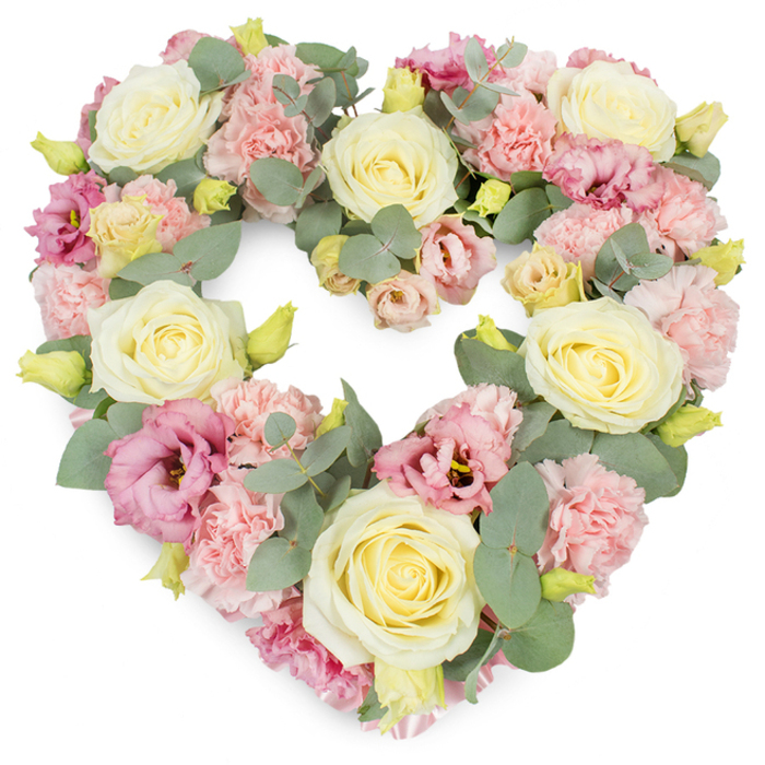 The image shows a luxuriously full, heart-shaped funeral wreath, meticulously crafted from pastel flowers and soft foliage, set against a bright white background that allows every petal to stand out. The heart form is complete and evenly proportioned, with no gaps, giving an immediate impression of abundance and careful, thoughtful floristry. Dominating the design are large cream and pale yellow roses, each bloom perfectly formed, their petals tightly coiled at the centre and then unfolding smoothly to create elegant, rounded heads that anchor the structure. Intertwined among the roses are plentiful pastel pink carnations, their delicate, fringed petals giving the arrangement a feathery, almost cloud-like texture that feels soothing to the eye. Richer tones appear through mauve and deeper pink lisianthus flowers, whose slightly more open, cupped shapes and sometimes darker throats provide subtle contrast and add depth, like soft shadows in the heart. Fine stems of silvery-green eucalyptus wind their way along the heart's outline and weave between the blooms, their cool, rounded leaves bringing a modern, natural touch and a gentle hint of woodland freshness. Small yellow-green flower buds are peppered throughout, evoking the idea of new beginnings even within a piece that speaks mainly of remembrance. The overall mood is one of calm love, sympathy, and respect, ideal for services in the Tulse Hill area, whether placed at a local church, crematorium, or graveside. With its harmonious blend of pink, cream, and green, this heart-shaped tribute offers a quiet, heartfelt way to say goodbye and to honour a life lived with kindness.